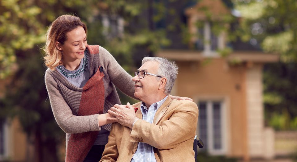 A Woman in a Sweater Behind a Man in a Wheelchair