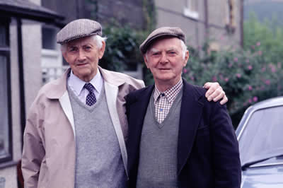 Two elder men standing side by side at the street