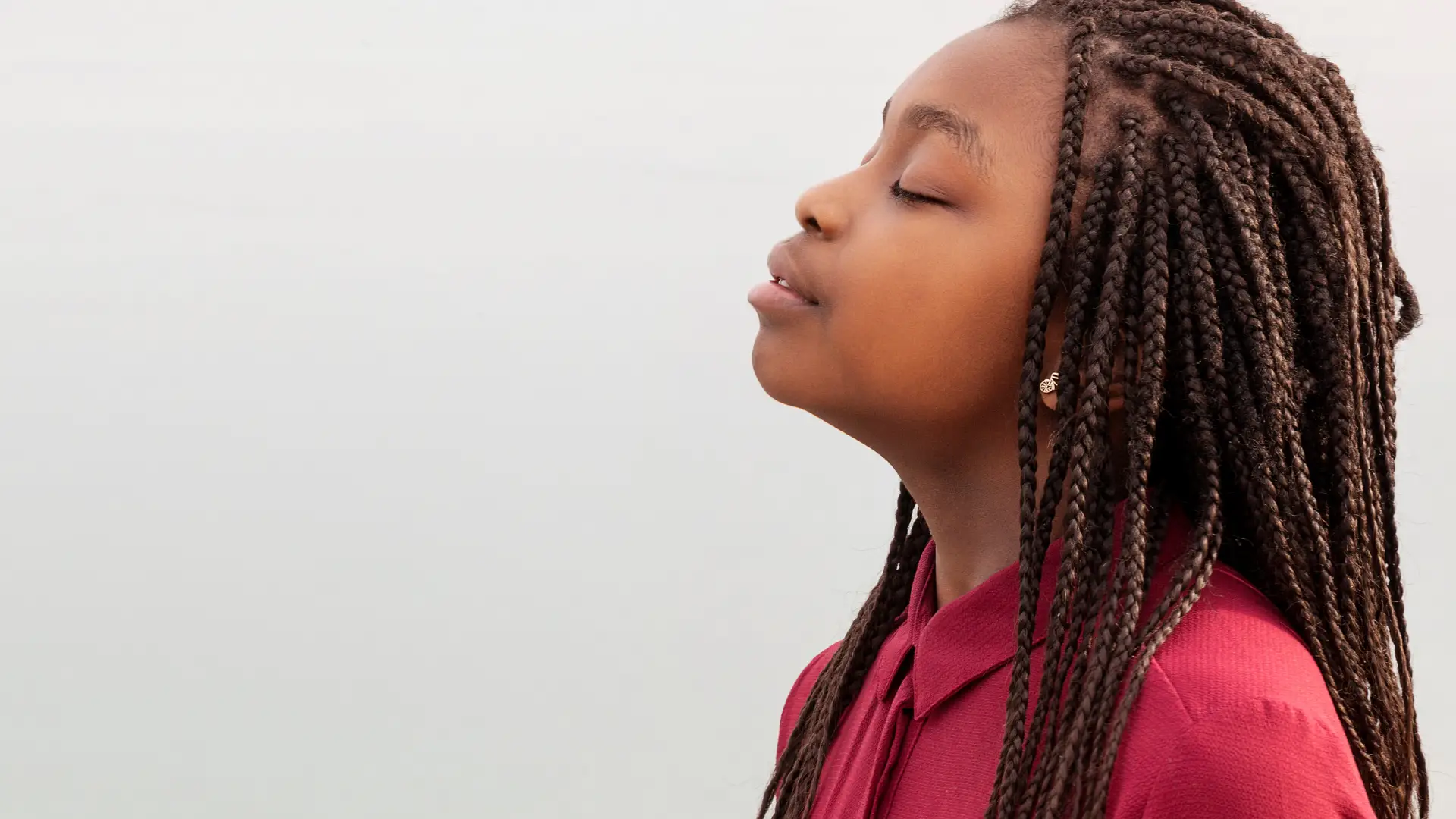 A young girl closing her eyes wearing a red shirt