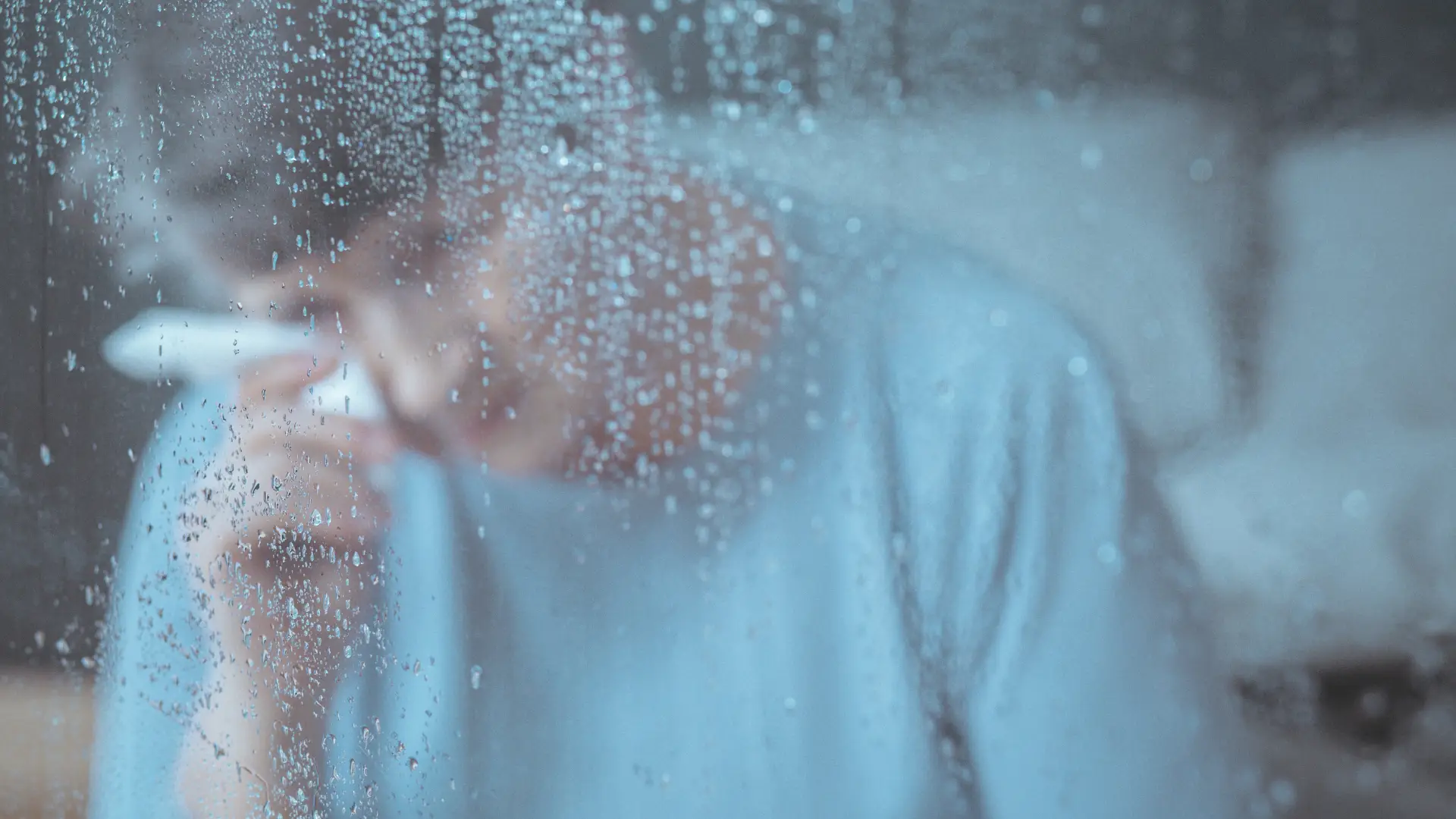 A person wiping his face on a rainy day