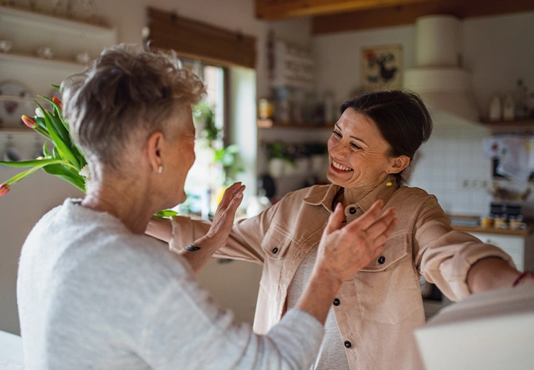 Two women greet each other with arms out to hug