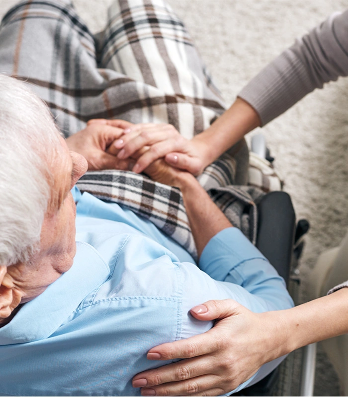 Caregiver reassuring senior in a wheelchair