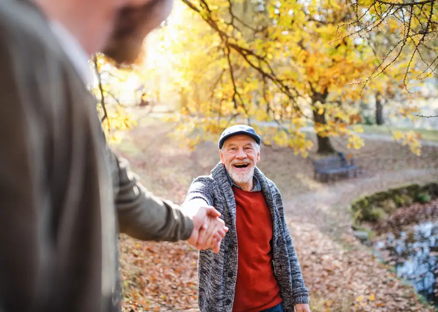 Two men hold hands outside during a walk