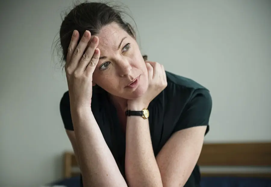 A woman looking stressed and thoughtful, resting her head on her hand.